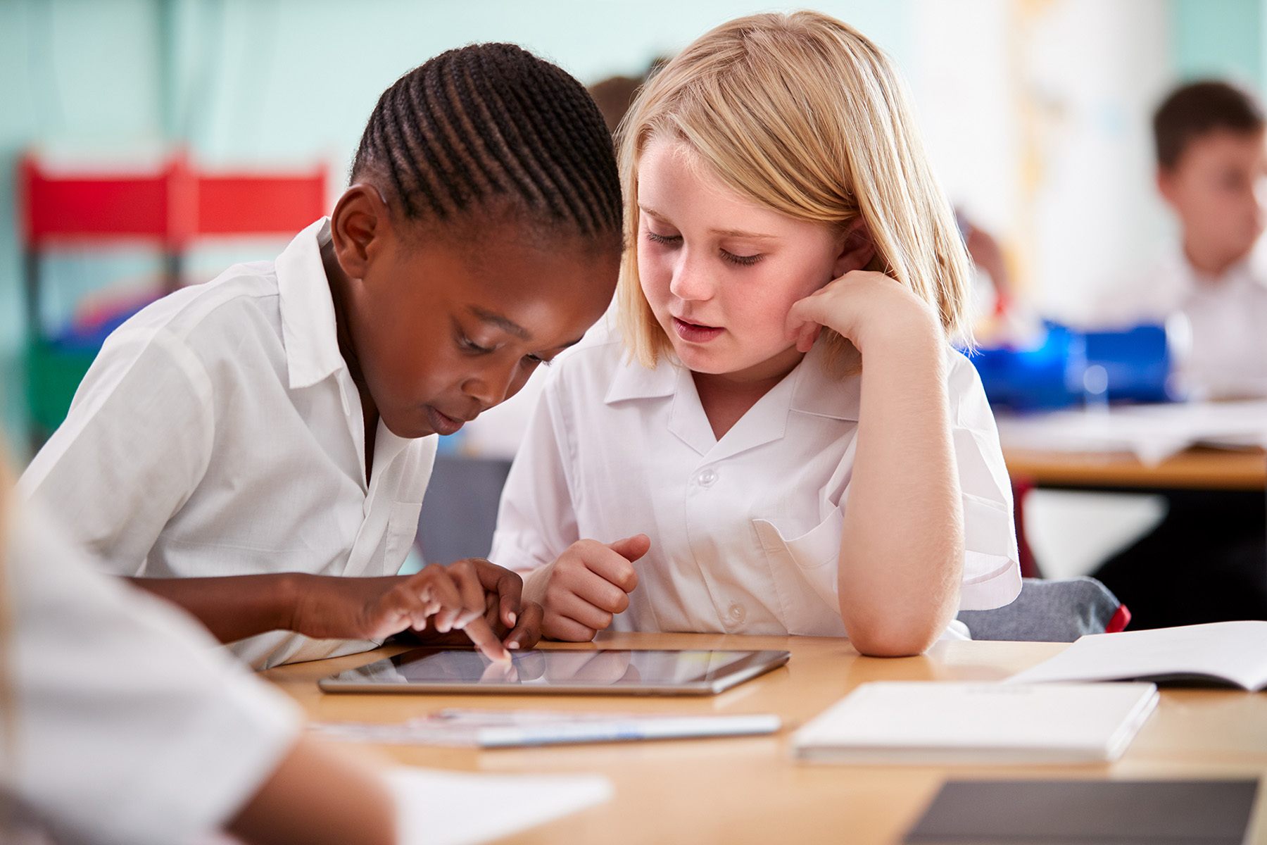 two students in school uniforms working with tablet